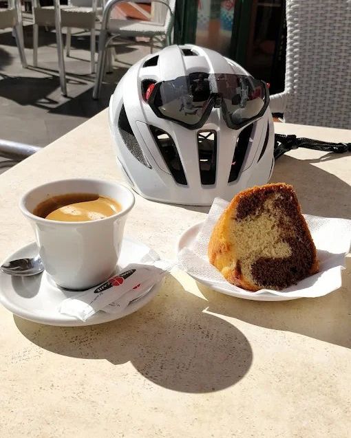 A white helmet with sunglasses, a coffee and a slice of marble cake on the terrace